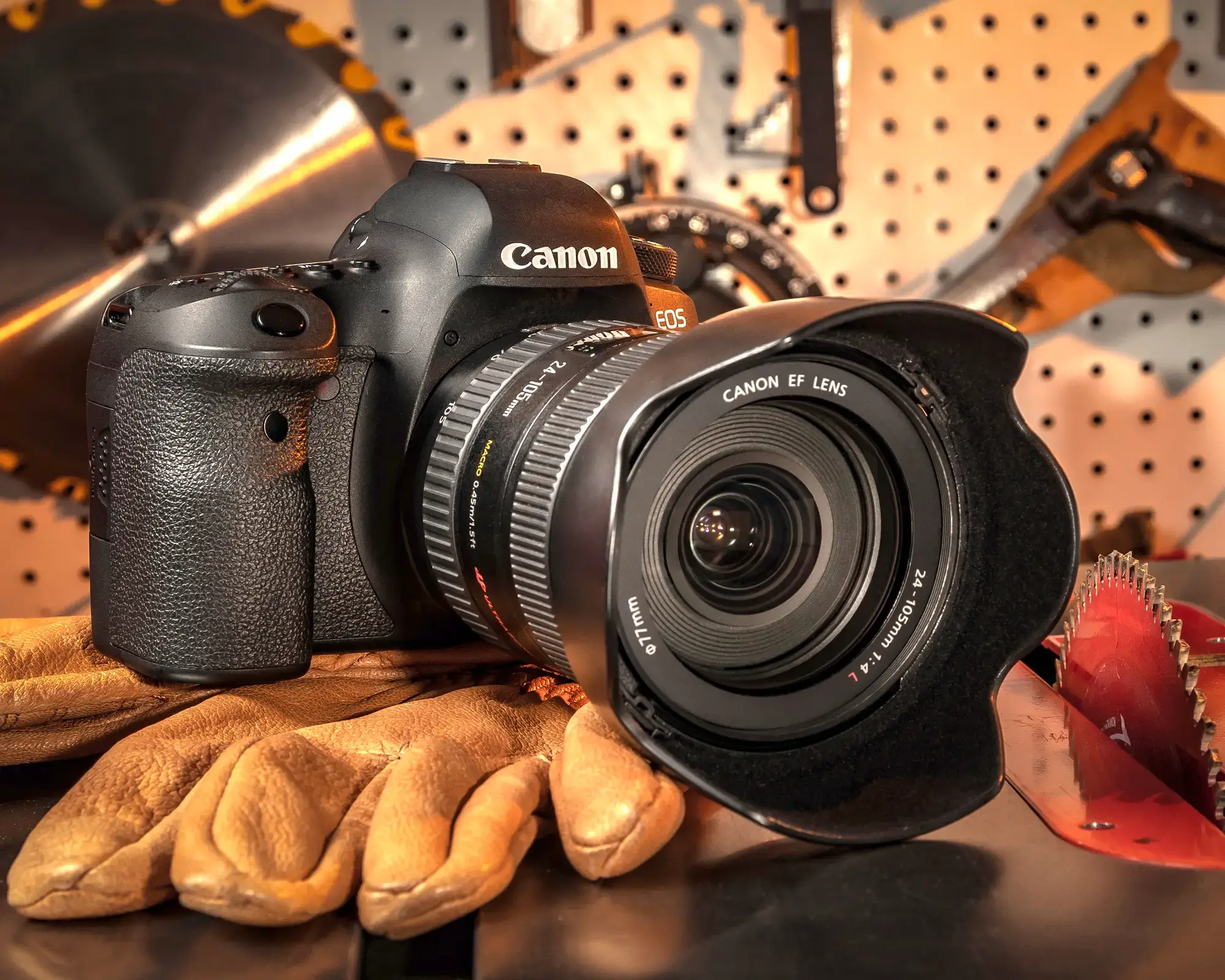 Canon camera on gloves with tools background.